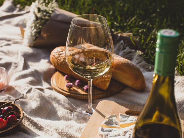 Picknick med vin, ost och bröd i solnedgång